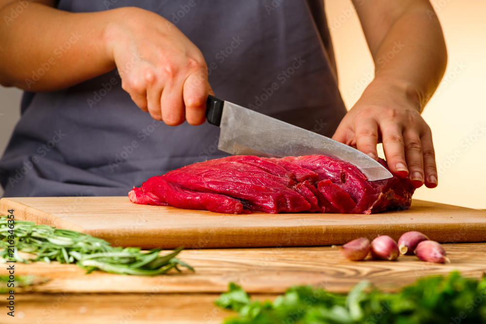 woman cuts fresh meat for cooking in the kitchen woman cuts fresh meat for cooking in the kitchen