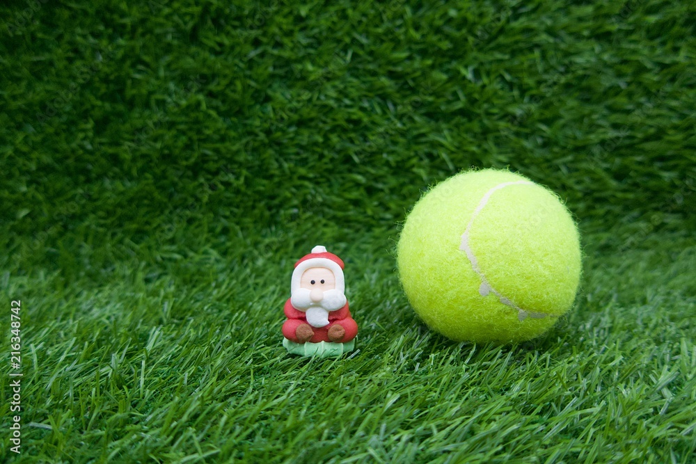 Naklejka premium Merry Christmas with Santa with tennis ball on green grass 