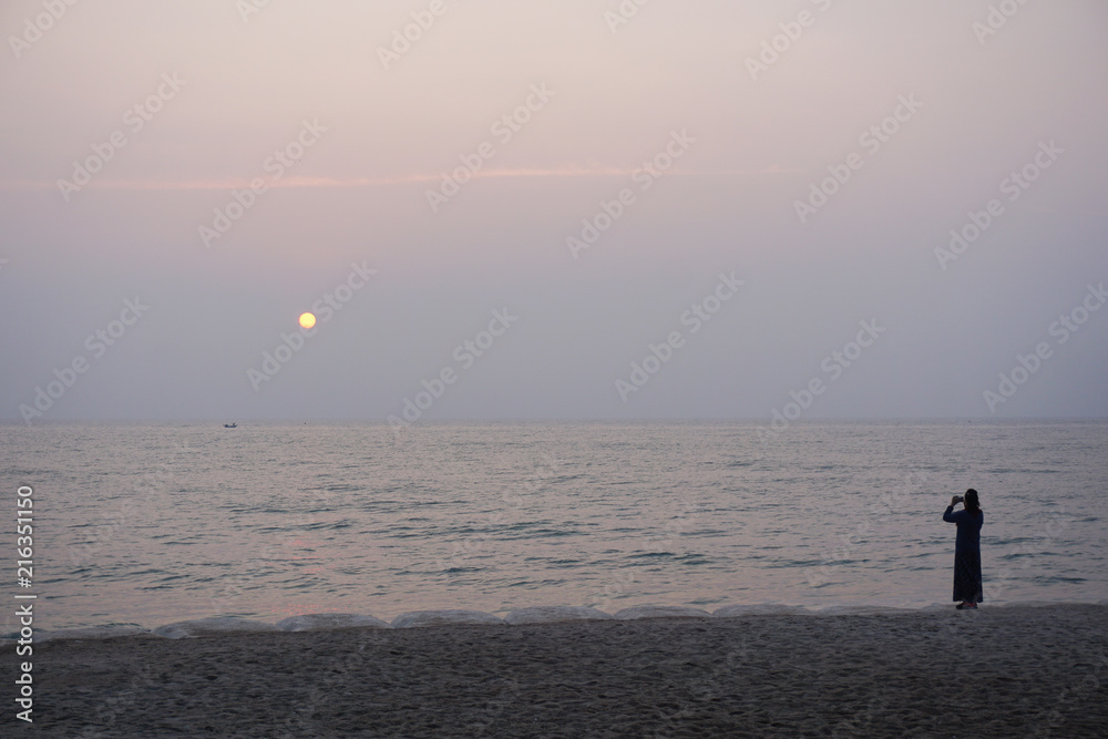 lonely woman standing at the beach when sunset