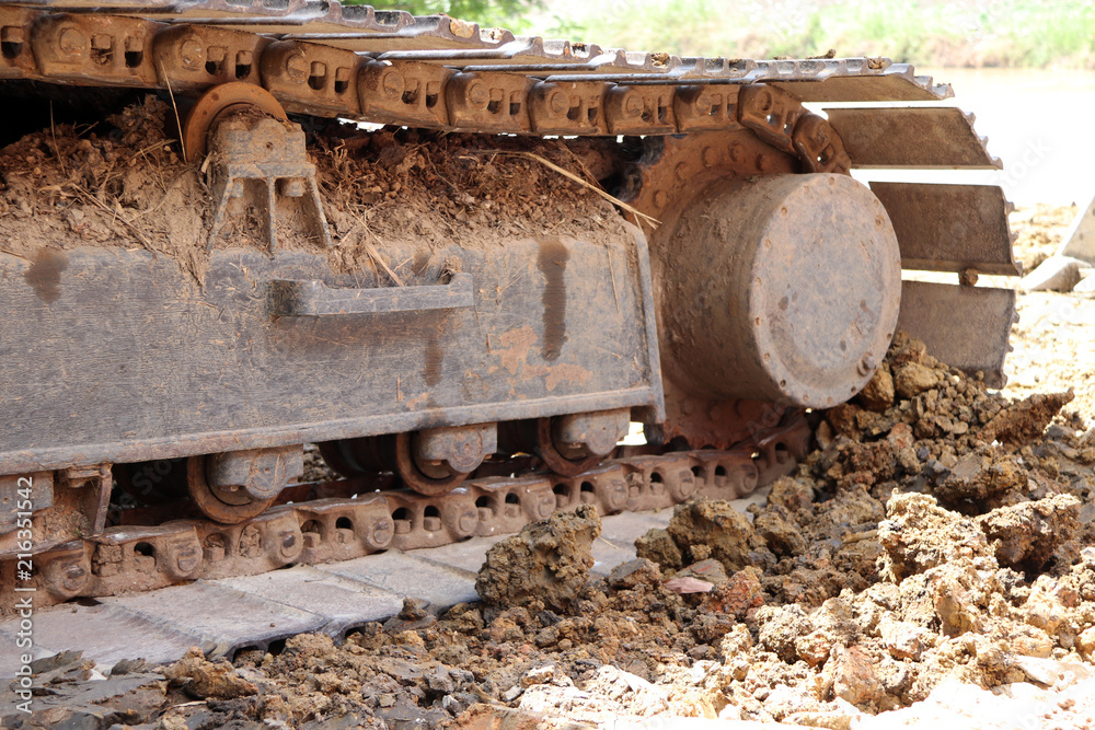 closeup Continuous tracks or Tracked wheel of excavator or backhoe on the soil floor. The aggressive treads of the tracks provide good traction in soft or hard surfaces. To be driven.
