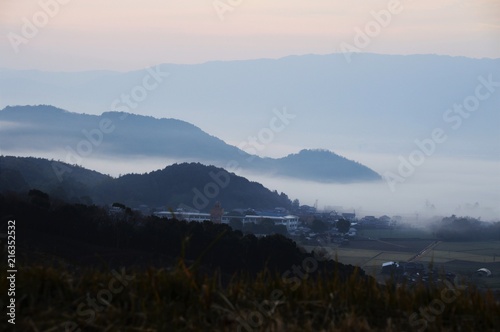 Rural town and mountains are covered with dense fog