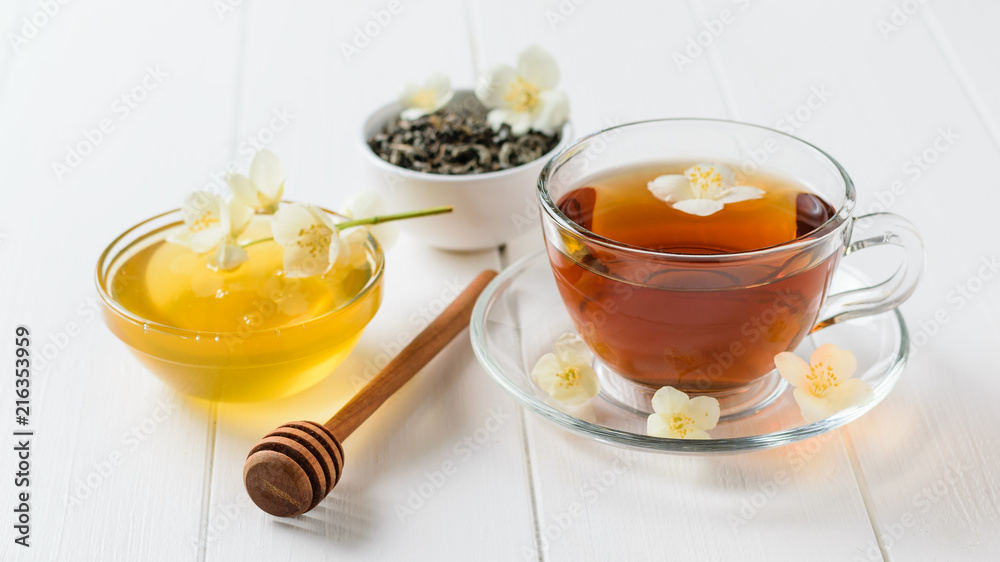 Freshly prepared jasmine tea with Jasmine flowers and honey on a rustic white table. Freshly prepared jasmine tea with Jasmine flowers and honey on a rustic white table.