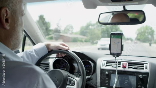 Man driving around as he taxis person checking his GPS making sure he goes to the right destination.