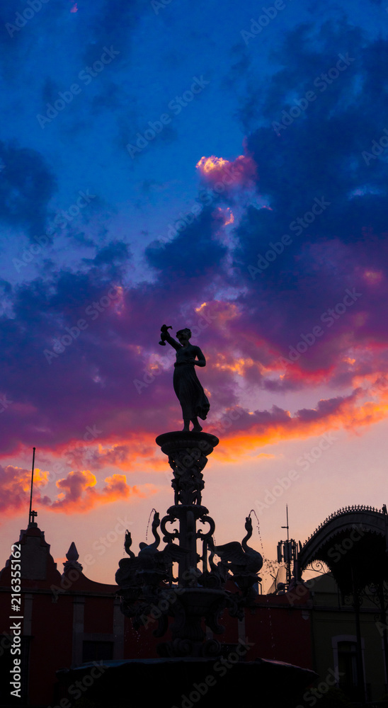 Satue and kiosk in backlight, colorful sunset scene with sky and clouds in Queretaro Mexico. Satue and kiosk in backlight, colorful sunset scene with sky and clouds in Queretaro Mexico.