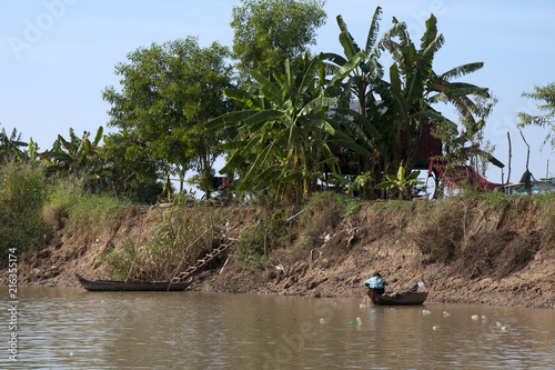 Sangker River, Battambang Cambodia, fisherman in wooden boat in late afternoon with recycled drink bottles as net buoys