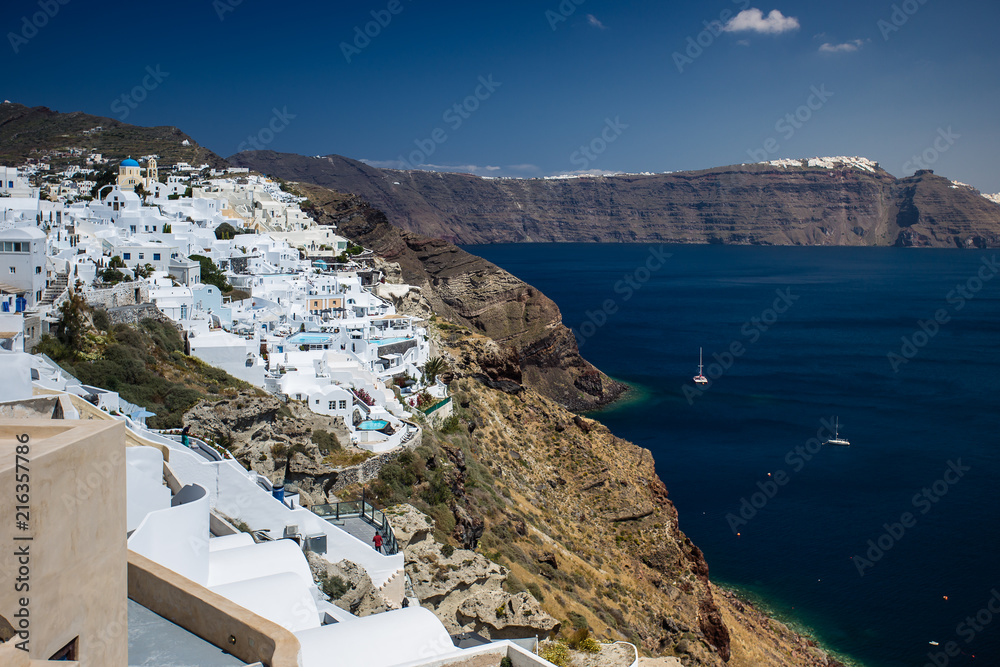 Gourgeous view from white walled town of Oia in Santorini, Greece, with ocean, cliffs and caldera of Santorini in the background.