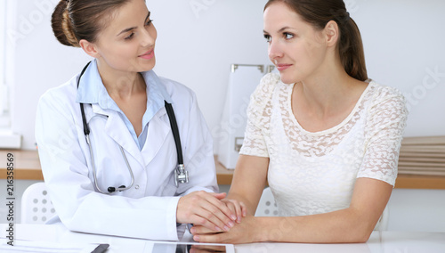 Doctor and patient having a pleasure talk while sitting at the desk at hospital office. Healthcare and medicine concept