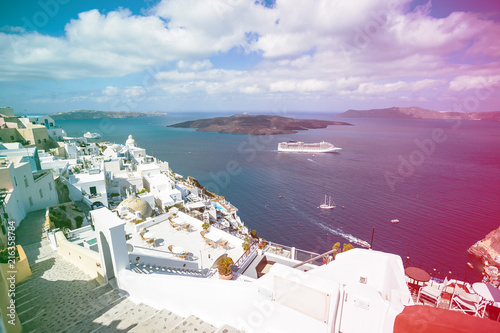 Gourgeous view from white walled town of Fira in Santorini, Greece, with ocean, cliffs and caldera of Santorini in the background. Colored light leak filter applied.