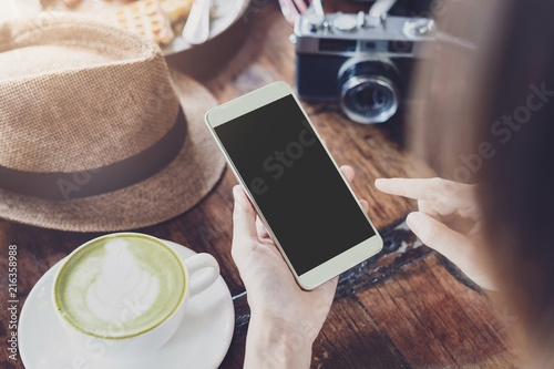 Young woman using smart phone and drinking coffee in cafe