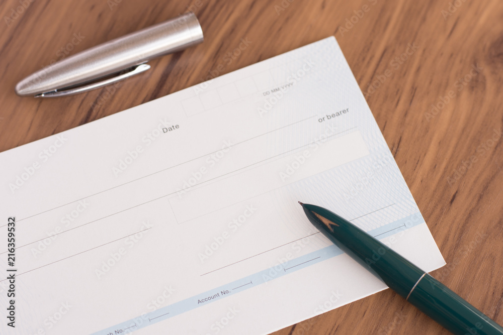 Cheque book and pen isolated on wood background. Cheque book and pen isolated on wood background.