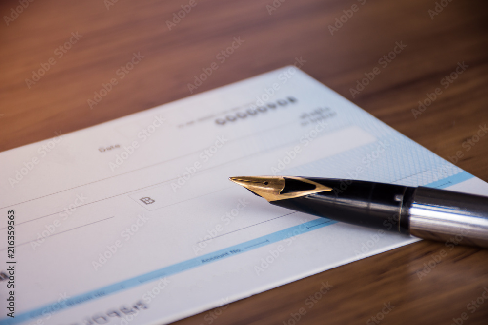 Cheque book and pen isolated on wood background. Cheque book and pen isolated on wood background.