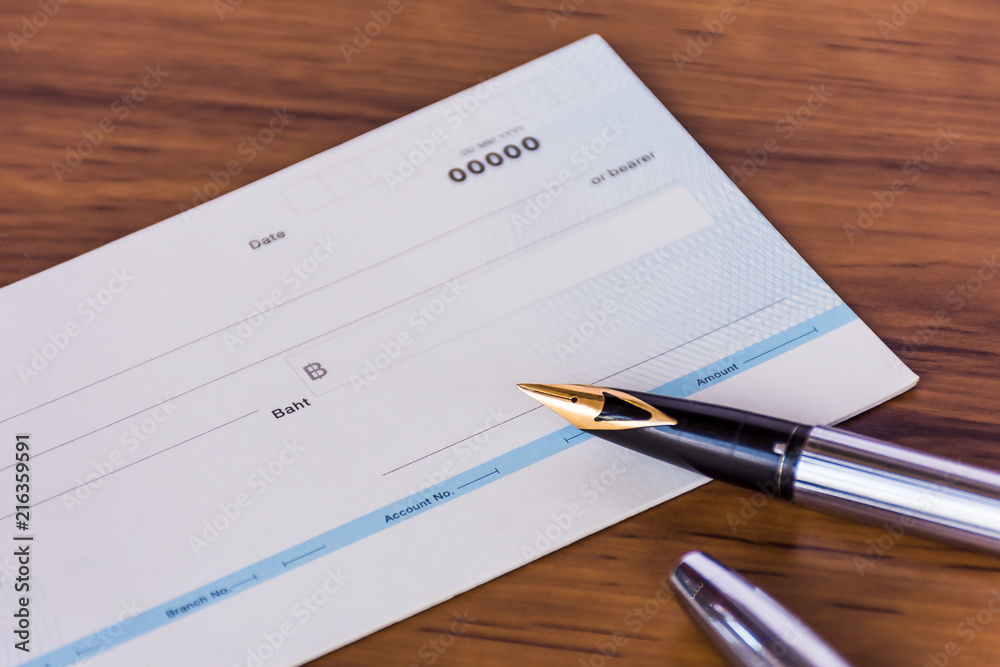 Cheque book and pen isolated on wood background. Cheque book and pen isolated on wood background.