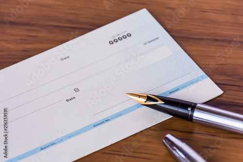 Cheque book and pen isolated on wood background.