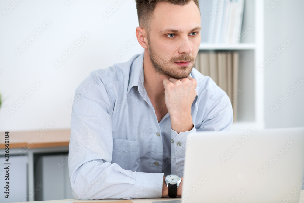 Portrait of businessman sitting at the desk in office workplace Portrait of businessman sitting at the desk in office workplace