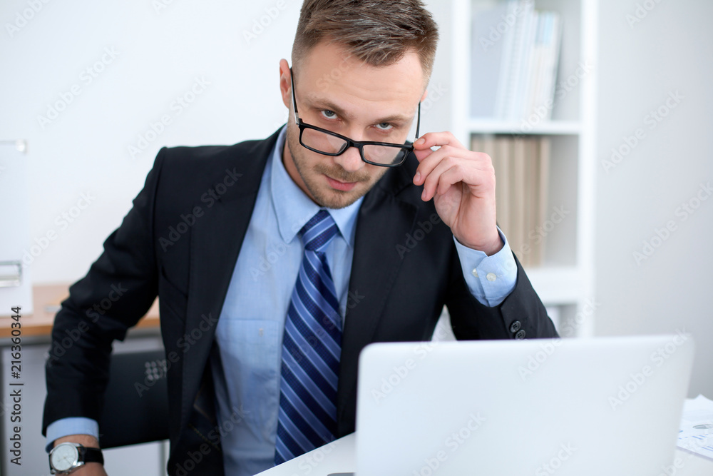 Portrait of businessman sitting at the desk in office workplace Portrait of businessman sitting at the desk in office workplace