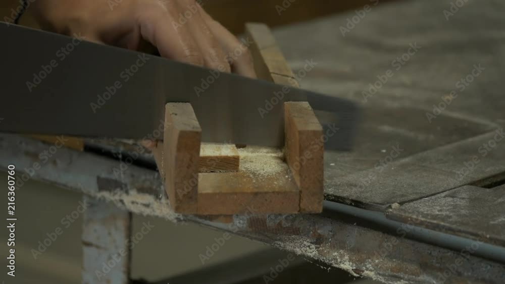 Cutting square timber with a handsaw from a side. Cutting square timber with a handsaw from a side.