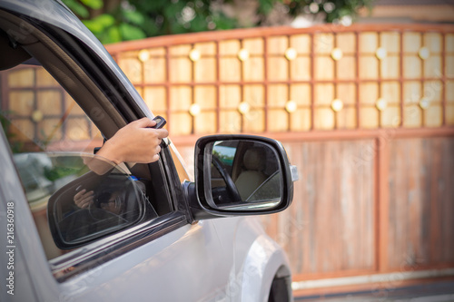 Female in car, hand holding and using remote control to open 