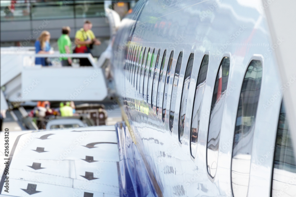 Close up of an airplane windows while people are going on board before a flight. Concept: travel, holiday, free time