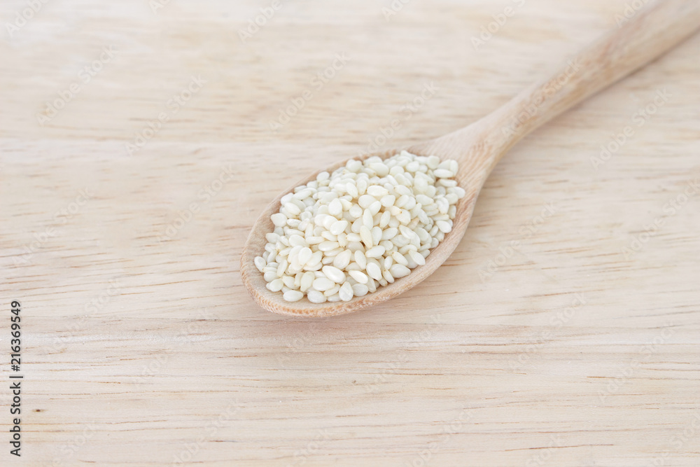 white sesame seeds in spoon on wood backgroud white sesame seeds in spoon on wood backgroud
