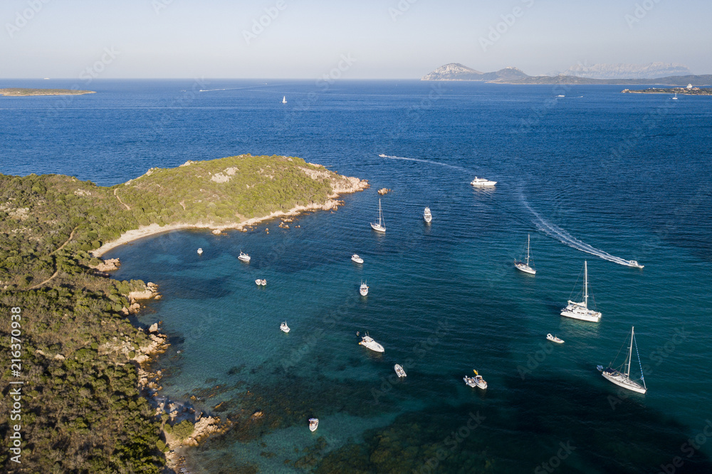 View from above, aerial picture of the amazing Emerald Coast with a turquoise and transparent Mediterranean sea full of luxury yachts and boats during the summer season, Sardinia, Italy.