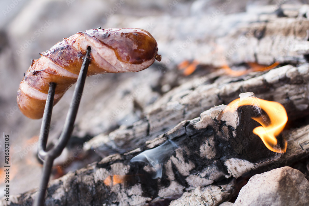 A sausage roasting on an open fire, campfire, travel dinner A sausage roasting on an open fire, campfire, travel dinner