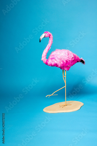 trend ceramic pink flamingo on a stand on the blue wall background like graphic resource