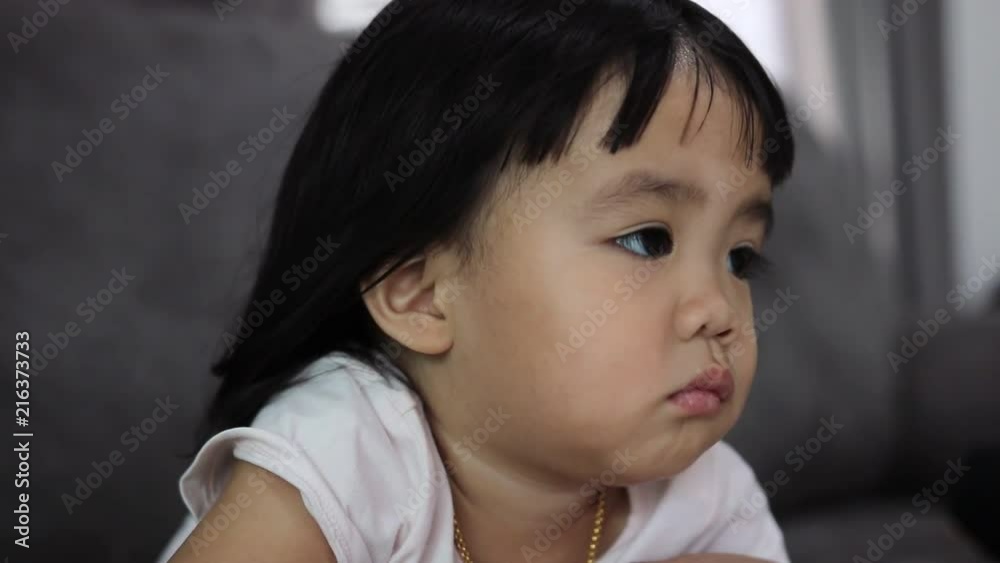 Baby asian girl watching TV on sofa at home. Baby asian girl watching TV on sofa at home.
