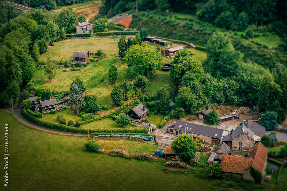 A vantage point view over a small farm in Ardennes, Belgium, with a miniature-like look and feel