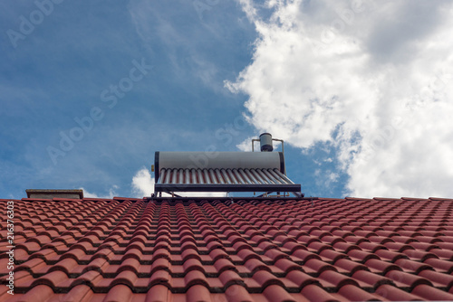 Solar water heater boiler on residentual house rooftop  blue sky with white sky background.