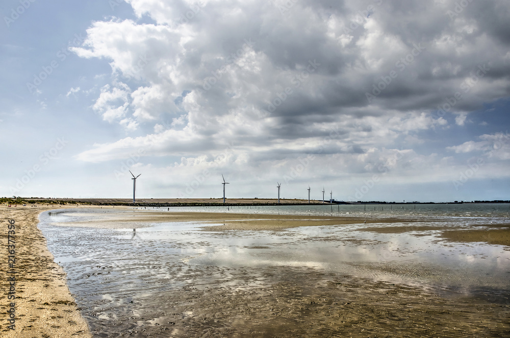 Clouds over the dam in Haringvliet estuary reflecting in shallow lakes on the beach near Rockanje, The Netherlands Clouds over the dam in Haringvliet estuary reflecting in shallow lakes on the beach near Rockanje, The Netherlands