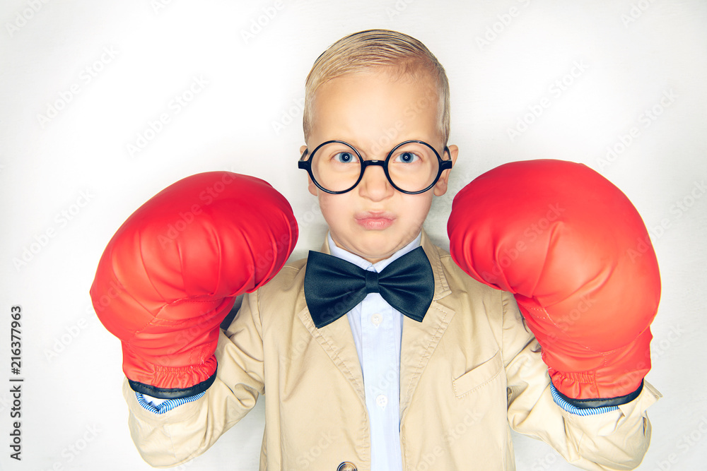 Little boy wearing a suit looking fearless with boxing gloves