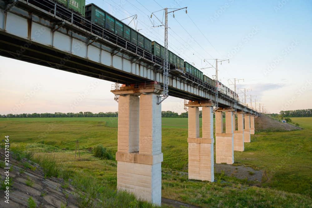 June 30, 2018: freight train passes bridge across the ravine at sunset of the day. Kanash. Chuvashia. Russia