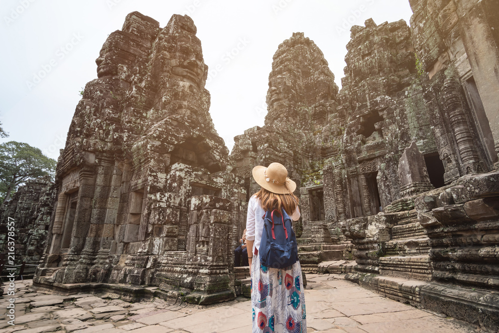 Obraz premium Young woman traveler visiting in Bayon temple at Angkor Wat complex, Khmer architecture heritage in Siem Reap, Cambodia