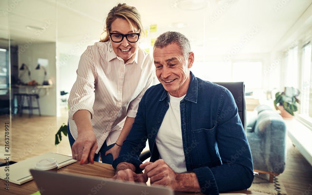 Smiling mature business colleagues talking together in an office Smiling mature business colleagues talking together in an office