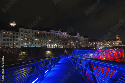 Graz bei Nacht: Brücke auf die weihnachtlich rot leuchtende Murinsel