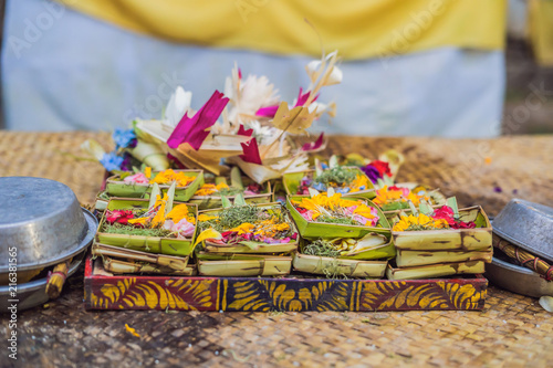Traditional balinese offerings to gods in Bali with flowers and aromatic sticks photo