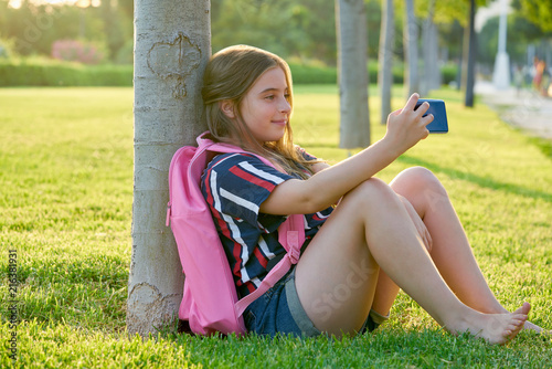 Blond student kid girl with smartphone in park
