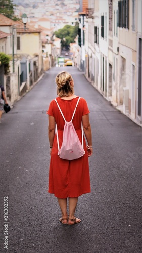 young woman in red dress standing in the street looking at buildings