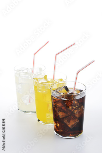 Refrescos de cola, naranja y limón en vaso con pajita sobre fondo blanco