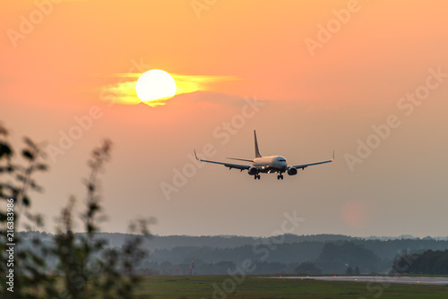 A plane approaches the airport during sunset.