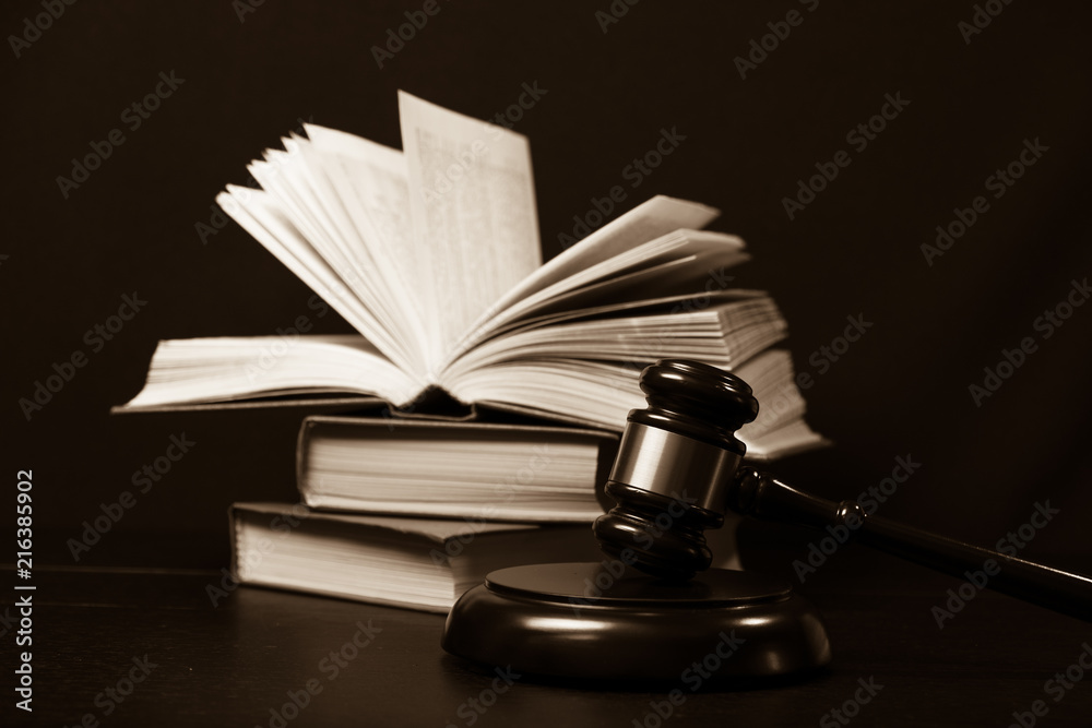 Judge gavel beside pile of books on wooden background Judge gavel beside pile of books on wooden background