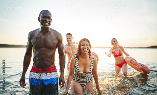 Laughing young friends wearing swimsuits splashing together in a