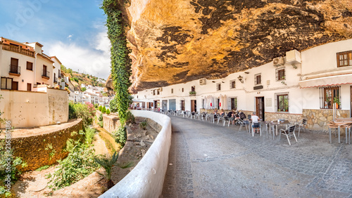 Restaurants in houses built in caves into rock overhangs above the Rio Trejo in the white village of Setenil de las Bodegas, Spain. photo