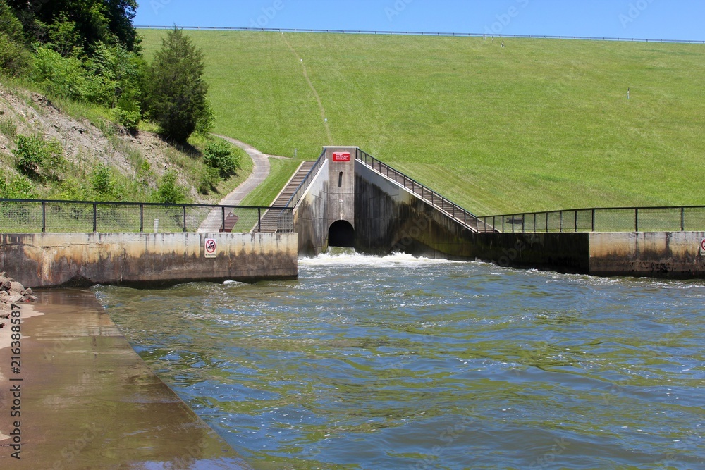 Fototapeta premium The open spillway flowing into the creek water.