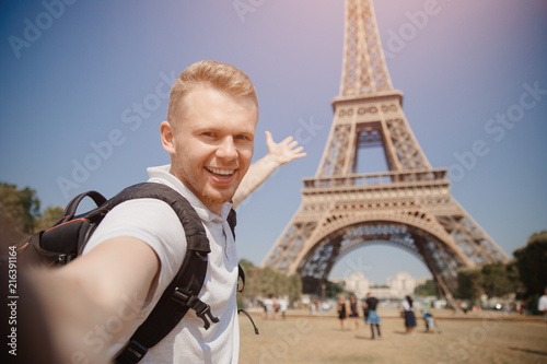 Male student doing selfie photo on background of Eiffel Tower in Paris, France. Concept travel, training, university.