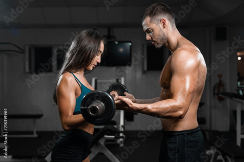 Man instructor and woman train, lifting dumbbells