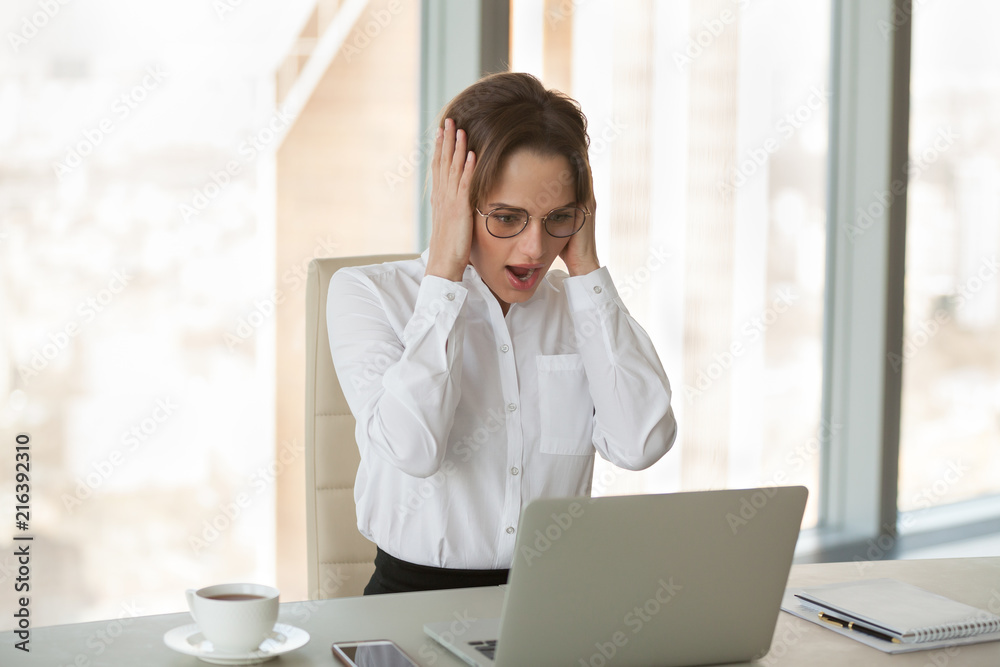 Shocked businesswoman reading morning business news, watching company rates falling, female ceo frustrated by unexpected laptop mistake or error message, woman observe sudden market crash or crisis Shocked businesswoman reading morning business news, watching company rates falling, female ceo frustrated by unexpected laptop mistake or error message, woman observe sudden market crash or crisis