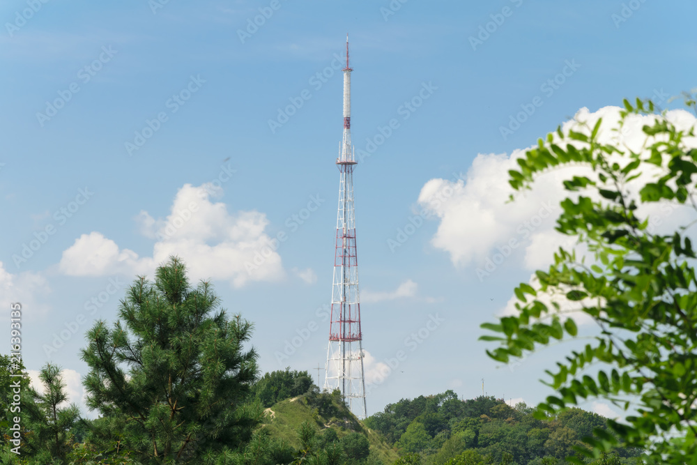 TV tower on a background of blue sky and green trees