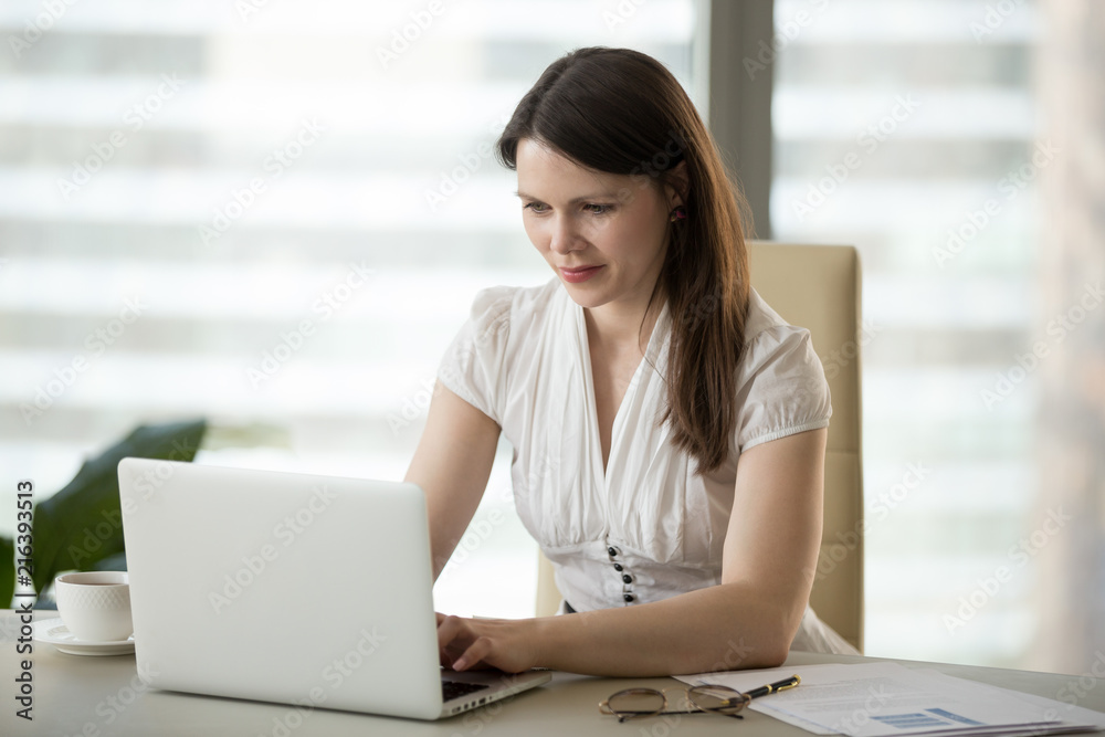 Millennial businesswoman working at laptop, typing business message to colleague or partner, female office worker browsing web, searching or reading news at computer, woman surfing internet Millennial businesswoman working at laptop, typing business message to colleague or partner, female office worker browsing web, searching or reading news at computer, woman surfing internet