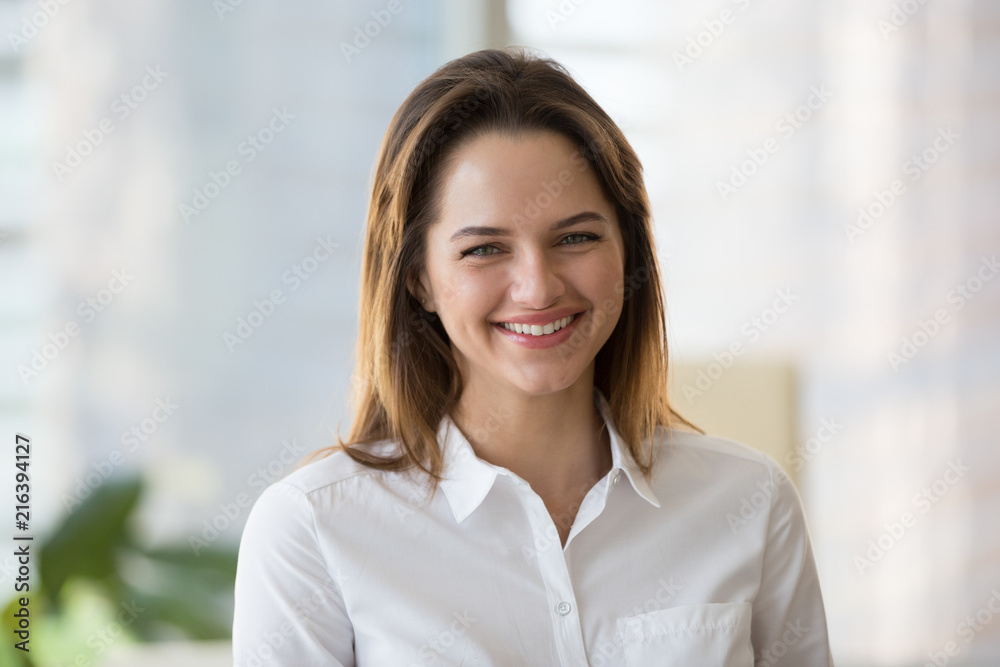 Portrait of happy millennial female office worker posing for picture at workplace, successful businesswoman smiling looking at camera, confident employee shooting for company advertising or catalogue Portrait of happy millennial female office worker posing for picture at workplace, successful businesswoman smiling looking at camera, confident employee shooting for company advertising or catalogue